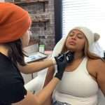 Kristen-Anne Thomas, FNP-BC, wearing black gloves and a beanie, administering Kybella injections under a patient’s chin for double chin reduction at Reviv Beauty Med Spa in Sanford, Florida.